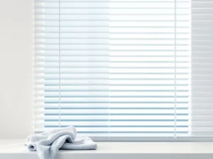 Witte plastic raamjaloezieën met waterdruppels en microfiber doek, toont reiniging van vuil naar schoon